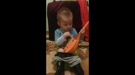 My nephew is sitting on a baby potty and playing the dombra