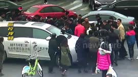 Passers-by help lift up a car to release woman trapped under it