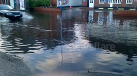 black car drives down flooded street in Egham