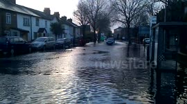car drives down flooded road in Egham