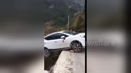 Car hangs off cliff edge in southwestern China