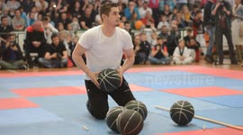 Juggler Suad Bajric is standing on its head off spinning two basketballs 