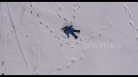 Aerial shot of a little girl making a snow angel in the snow, 4K