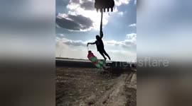 Construction worker dances with dummy while hanging on excavator