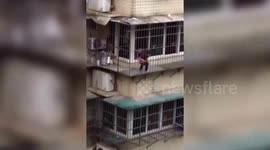 Toddler plays on security net outside the window on fourth floor