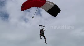 Man lands parachute with one hand while holding his groin