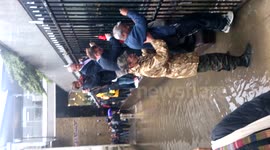 London rain - Man helps people cross flood at Blackfriars Bridge south bank