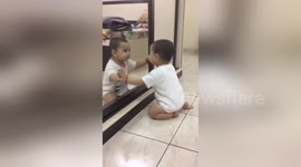 Newsflare Edit - Cute baby amused to see himself in mirror