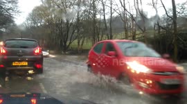 Cars drive through flooded roads in Cumbria