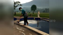 Newsflare Edit - Balinese man sweeping up volcanic ash during volcano eruption.