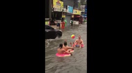 British tourists play on inflatable rubber rings in flood