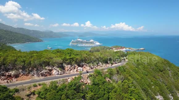 Drone flying reveal of Caribbean cruise ship behind mountain