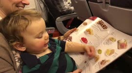Toddler tries to pick up and eat photos of food from menu