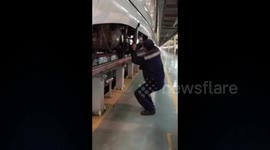 Railway worker checks components on bullet train in lightning speed