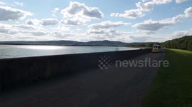 Small tourist train on road around a lake
