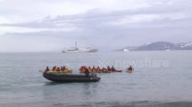 Polar kayakers saluting - with the Akademik Ioffe in the background