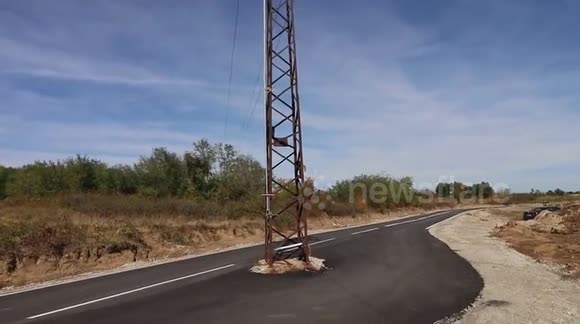 High voltage electric pole sits in middle of brand new road in Bulgaria
