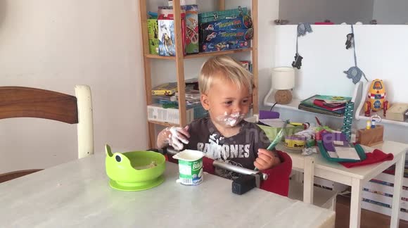 Baby eats yoghurt with hands