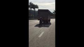 The cyclist man followed the truck to avoid the sun and wind