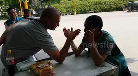 Small Chinese guy arm wrestles white guy