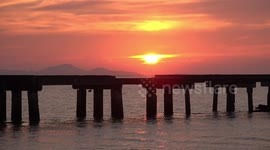 Jogger running on a bridge with a beautiful ocean sunset in the background.