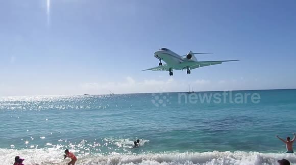 Aircraft flies over tourists' heads at Caribbean beach before airport landing