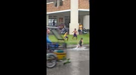 Children in Philippines roll about in puddles during flood season