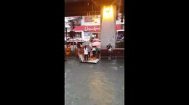 Children play in flooded road in the Philippines, adults cross on wooden raft