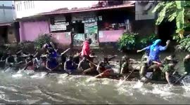 Indian club practices for boat race on flooded road in town