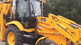 Friends of a much loved digger driver transport his coffin to his funeral in the bucket of a JCB