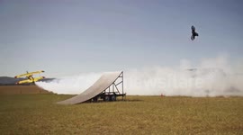Motocross rider backflips over stunt plane