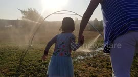 Grandma Runs Through Sprinkler with Granddaughter