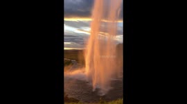 Gorgeous sunset shines through Icelandic waterfall