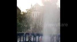 Burst water main sprays water into the air on residential London road