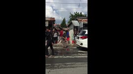 People line up over a kilometre waiting to fill plastic containers of petrol. Shortages of petrol in Palu Sulawesi have meant petrol stations are guarded by the military with machine guns.