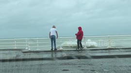 Two grown men play chicken with the tide in Aberystwyth