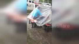 Mahjong players use plastic sheet to avoid rain