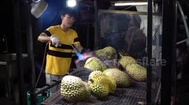 These tourists are eating durian flame-grilled with a blow torch