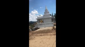 Buddhist monks watch in disbelief as 'lucky' temple slides into river after heavy rain