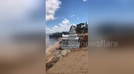 Buddhist monks watch in disbelief as 'lucky' temple slides into river after heavy rain