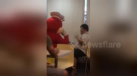 Fast food worker in cuddly bee costume entertains boy with Down syndrome eating alone