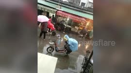 Small boy keeps his mum's bike seat dry in the rain with his own body