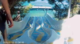 Kids going down a water slide into the sea