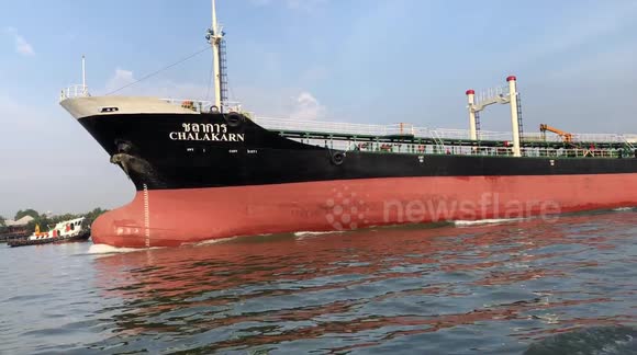 A large cargo tanker boat slowly goes down a river in Bangkok, Thailand