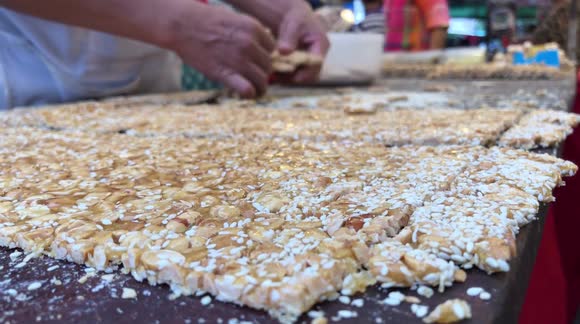 A Large Slab of Peanuts in Sugar being Cut