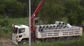 Unloading concrete pipes from a truck, six at a time.