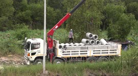Unloading large concrete pipes from a truck.