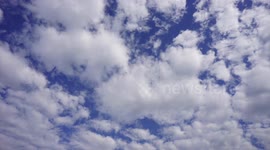 Time-lapse of white clouds moving across a blue sky.