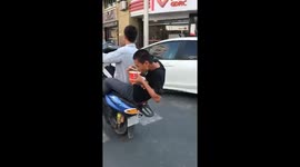广东河源  两男子一边摩托掂头一边吃面