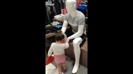 Adorable moment polite toddler greets mannequins inside shopping mall
